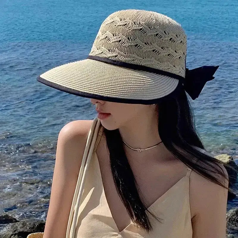 Stylish woman wearing a fashionable straw hats for women by The Lady's Haven Boutique near the water
